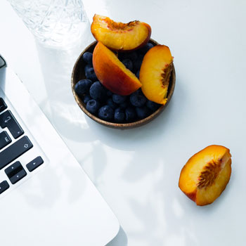 Bol de fruits à côté d'un ordinateur portable